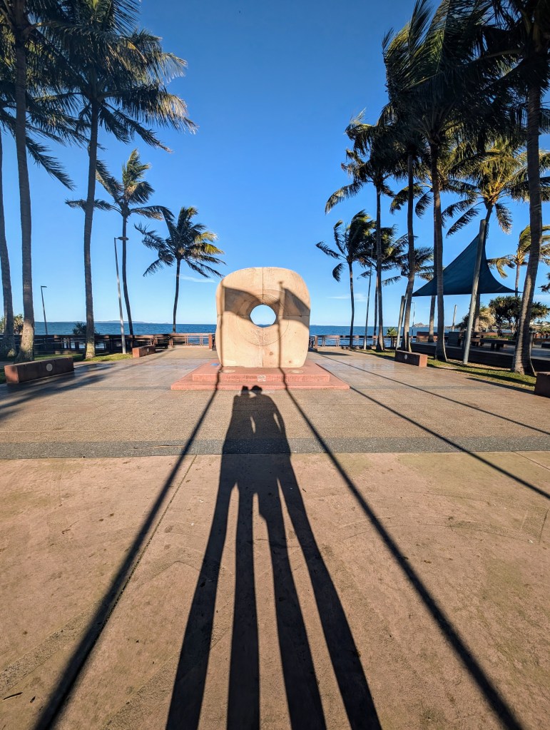 Yeppoon beach foreshore late in the day with palm trees and shadow of two people